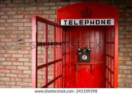 Close Up of Red Telephone Booth with Old Fashioned Telephone and Open Door