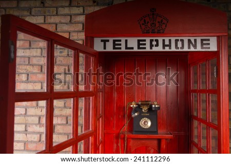 Close Up Detail of Red Public Telephone Booth with Old Fashioned Telephone Inside and Open Door