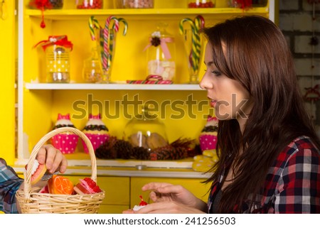 Close up Young Woman in Checkered Shirt Sitting at the Shop with Basket Filled with Pastries on the Table.