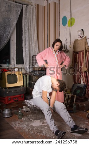 Angry Young Woman in Pink Robe Watching her Sleeping Partner Sitting on Cage at Junk Room.