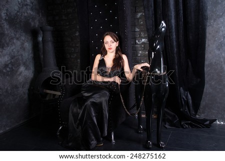Woman Wearing Black Formal Dress Sitting on Throne with Hand on Dog Statue Wearing Leash