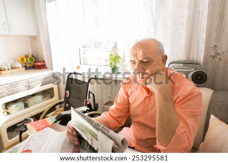 Close up Focused Old Man Reading Newspaper While Sitting at his Table at the Living Room