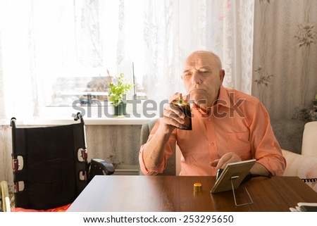 Close up Sitting Old Bald Man in orange Shirt Holding a Bottle Spray of Aftershave after Cleaning his Face at the Living Room.