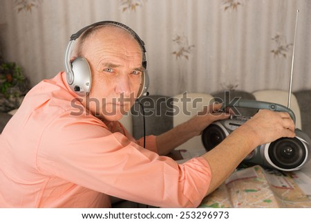Close up Bald Elderly Listening Music at the Cassette Player with Headset While Looking at Camera.