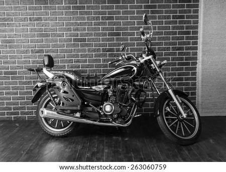 Black and White Full Length Profile Image of Motorcycle in front of Interior Brick Wall
