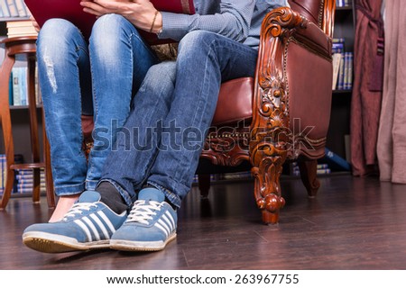 Close up Legs and Feet in Casual Clothing of a Sweet Couple Sitting on One Classic Chair