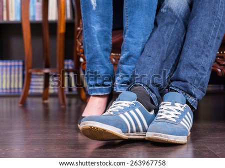 Close up Legs and Feet of a Couple Wearing Jeans and Shoes on the Wooden Floor.