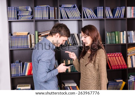 Half Body Shot of a Young Woman Telling his Man What to Message on Mobile Phone While Standing Inside the Library