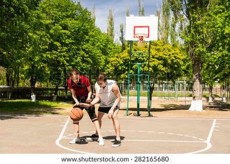 Young Athletic Couple Playing Basketball Together on Outdoor Court in Lush Green Park