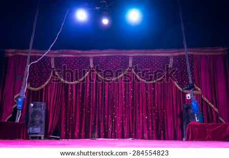 Colorful magenta curtains on a stage with bright shining spotlights inside a tent or marquis getting ready for a performance