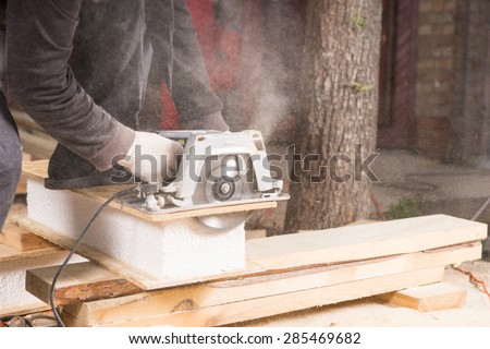 Close Up of Unrecognizable Man Using Hand Held Power Saw to Cut Planks of Wood for Home Construction