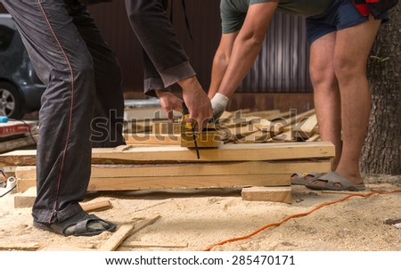 Two Unrecognizable Men Wearing Sandals Cutting Wood Planks on Informal Construction Site of New Home