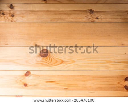 Background texture of a wooden table or floor with parallel planks with knots and a distinct wood grain pattern in a light wood, full frame