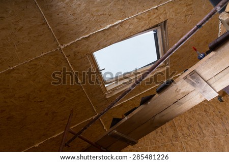 Low Angle View of Ceiling Sky Light in Unfishined Home with Exposed Particle Plywood Board and Fresh Caulking and Plank Scaffolding