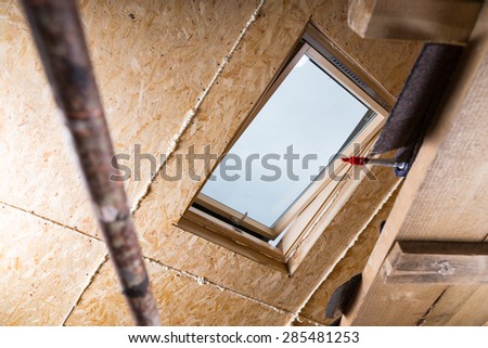 Low Angle View of Ceiling Sky Light in Unfishined Home with Exposed Particle Plywood Board and Fresh Caulking and Scaffolding