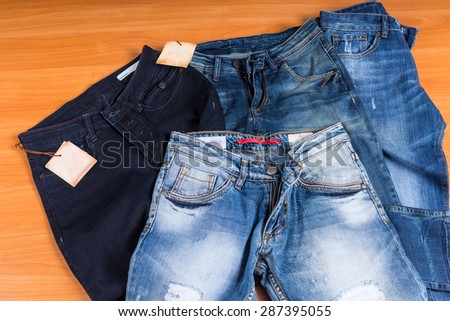 High Angle View of Pile of Front Facing Blue Jeans in Various Color Washes and Styles on Wooden Surface Background