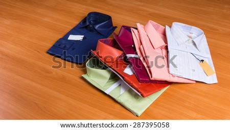 Collection of Colorful New Mens Dress Shirts, Folded with Tags Attached and Fanned Out on Wooden Surface