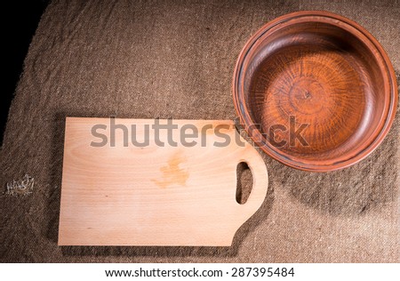 High Angle View of Handcrafted Wooden Cutting Board and Carved Wood Bowl on Burlap Covered Table Surface as seen from Directly Above
