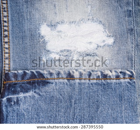 Extreme Close Up of Distressed Blue Jeans - Detail of Frayed Rip in Faded Demin Pant Leg Folded with Hem