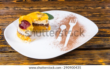 Close Up of Decadent Individual Fruit Cake Cut in Half and Served on White Platter with Dusted Cocoa on Wooden Table Surface
