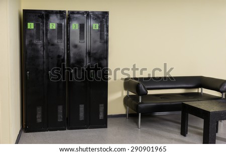 Interior of Locker Room Furnished with Four Black Lockers, Modern Padded Bench and Modular Table