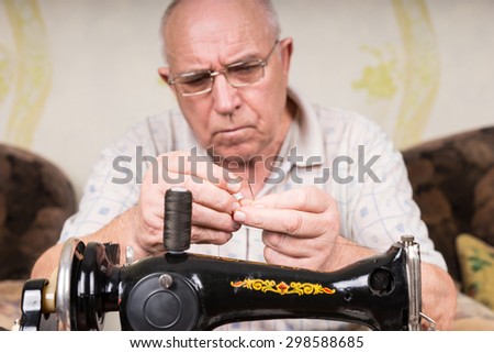 Close Up of Senior Man in Deep Concentration Threading Needle of Old Fashioned Manual Sewing Machine