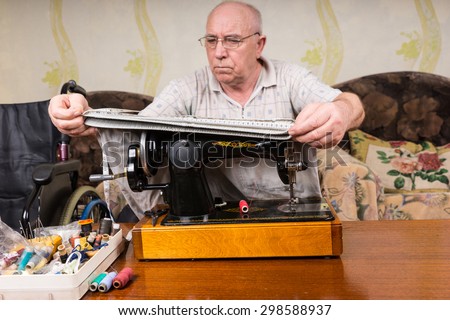 Senior Man at Old Fashioned Sewing Machine Measuring Pant Legs at Home in Living Room