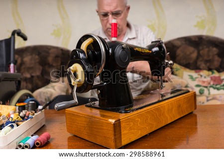 Close Up of Old Fashioned Sewing Machine Surrounded by Various Colorful Threads - Senior Man Behind Vintage Sewing Machine in Living Room