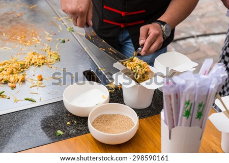 Close Up of Chef Serving Single Portion of Stir Fried Noodles in Chinese Take Out Box