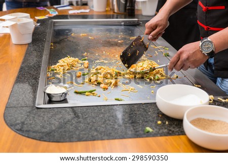 Close Up of Chef Preparing Single Serving Portions of Stir Fried Noodles on Flat Top Grill