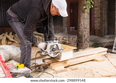 Man Using Hand Held Power Saw to Cut Planks of Wood for Home Construction Leaving Piles of Saw Dust on Floor