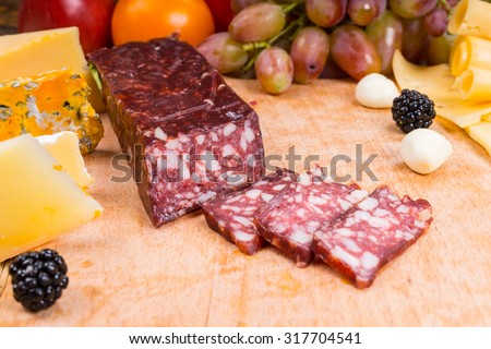 Close Up of Sliced Cured Meat on Gourmet Cheese Board with Variety of Cheeses and Garnished with Fruit