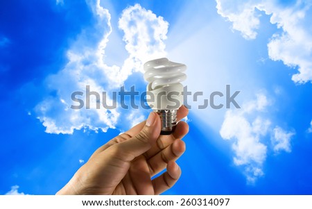 Electric bulb in hand on  blue sky background