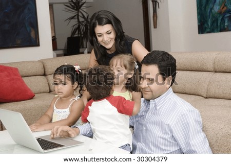 Portrait of family, mom, dad and their children enjoying indoor with a laptop