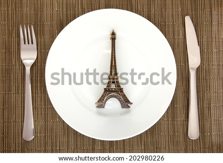 table setting of plate, fork, knife and Eiffel tower knife on dark background