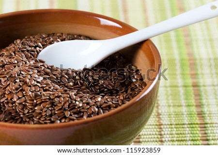 Brown flax seeds in brown green bowl with a white ceramic spoon ,Flax seed