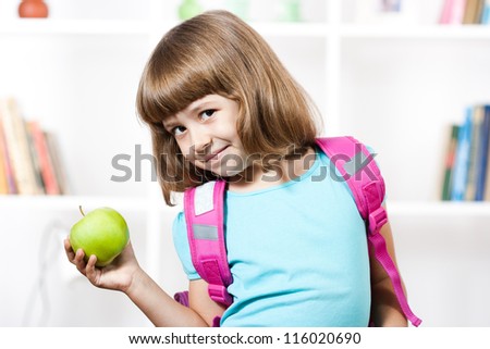 Little girl with backpack holding apple in her hand,Schoolgirl with apple