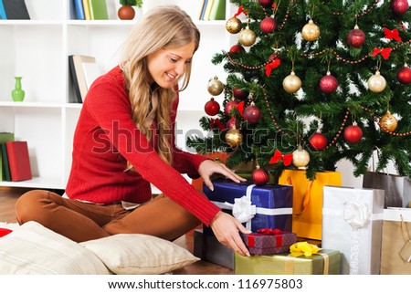 Young woman is putting gifts under Christmas tree,Young woman with Christmas presents