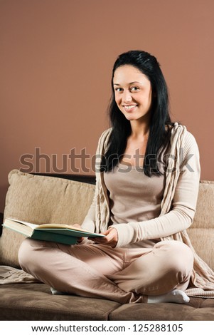 Beautiful young woman sitting on the sofa and reading a book,Young woman with a book