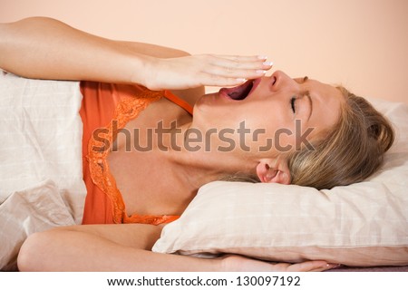 Young woman lying in bed and yawning,Woman yawning