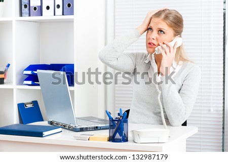 Worried businesswoman sitting in her office and talking on the phone,Concerned businesswoman