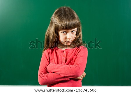 Portrait of angry little girl in front of blackboard,Angry little girl