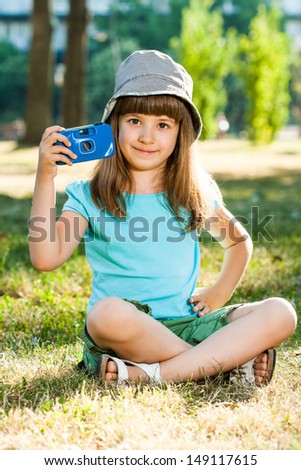 Cute little girl sitting in park and holding photo camera,Little photographer
