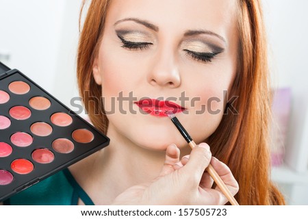 Photo of make up artist applying lipstick on a beautiful woman,Make up