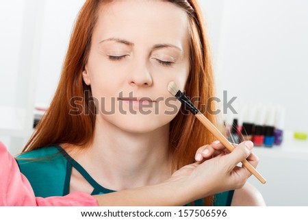 Photo of make up artist applying face powder to a beautiful woman,Make up