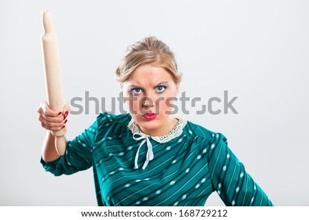 Portrait of angry retro housewife holding rolling pin,Angry retro housewife