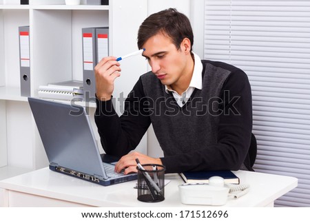 Young businessman sitting in his office,working on his laptop  and thinking about something,Businessman thinking