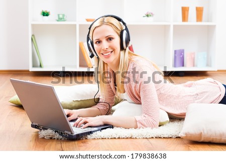 Beautiful blonde woman with headphones using laptop at her home,Woman  with headphones using laptop