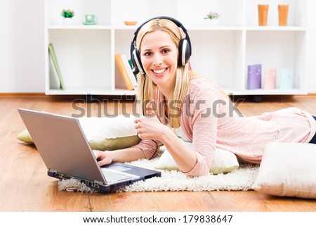 Beautiful blonde woman with headphones using laptop and showing thumb up,Woman  with headphones using laptop