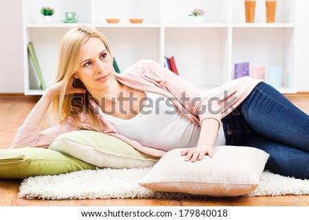 Beautiful blonde lying on carpet in her living room and thinking about something,Woman thinking